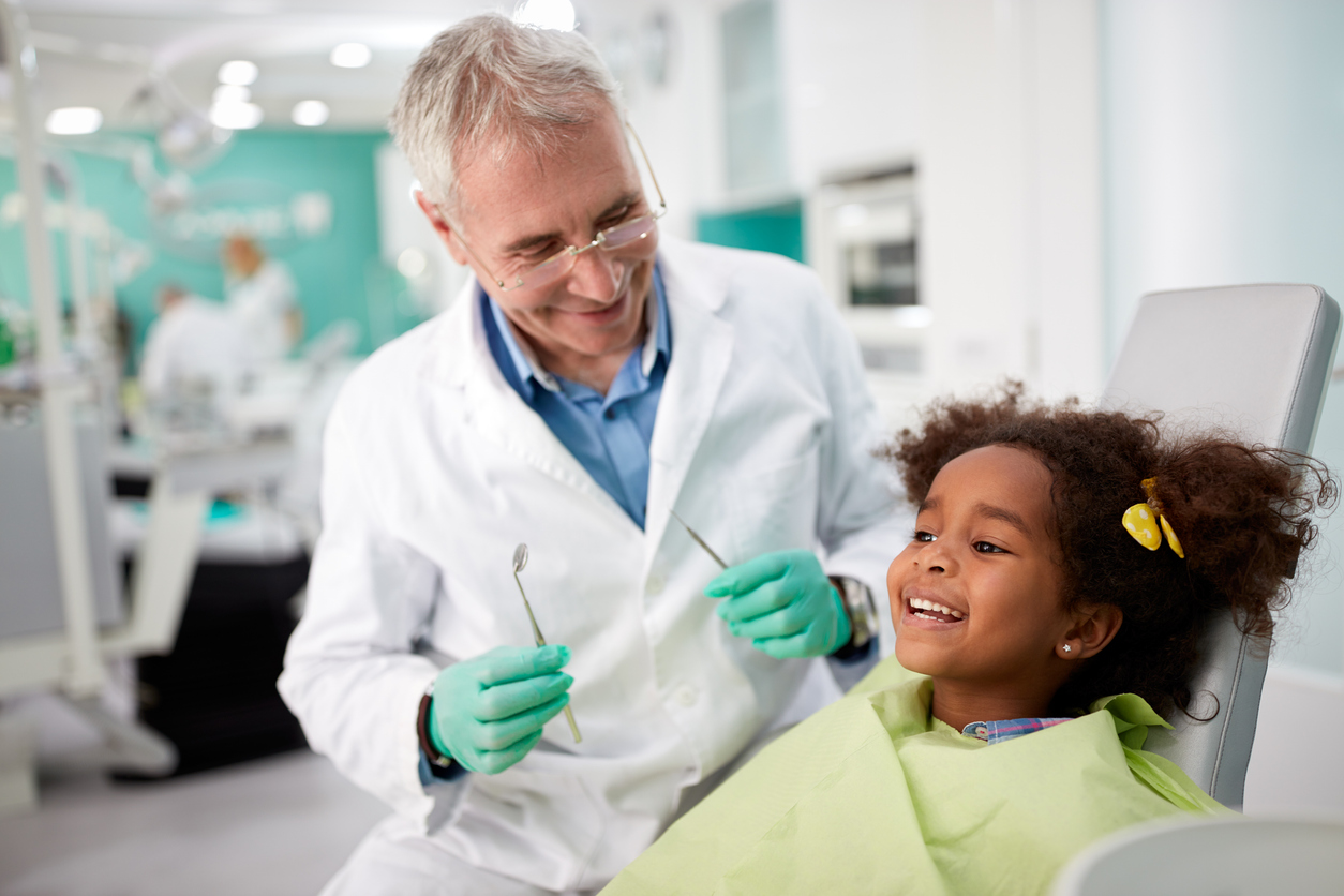 The image shows a kid at the dentist smiling to explain how often your child should visit the dentist.
